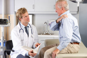 Doctor examining elderly male patient for shoulder instability
