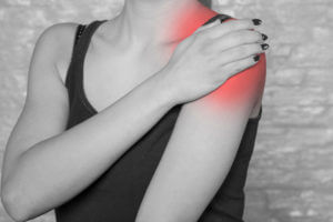 An image of a woman experiencing shoulder pain from a work injury due to shoulder dislocation.