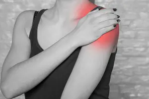 An image of a woman experiencing shoulder pain from a work injury due to shoulder dislocation.