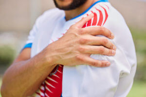 A sportsman puts holds his shoulder in pain after a training game due to torn rotator cuffs.