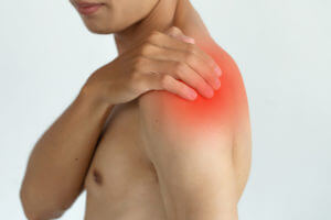 Close-up image of man touching his shoulder with red highlight showing pain caused by arthritic shoulder pain.