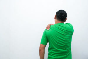 Man with shoulder pain caused by frozen shoulder in an isolated white.